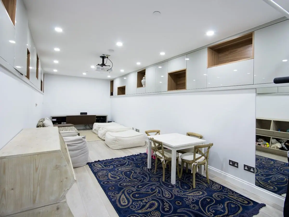 The finished basement living space with fitted storage and lighting