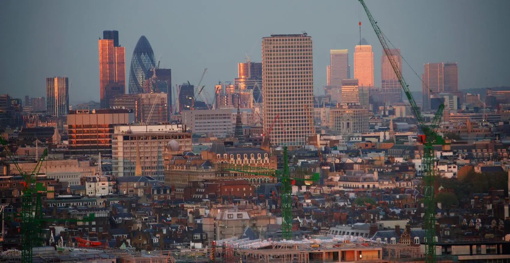 The London skyline at dusk, cranes over the City
